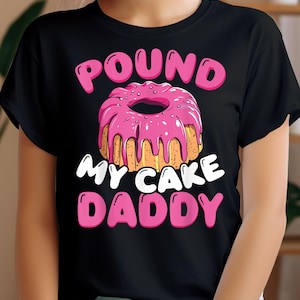 Puede incluir: Camiseta negra con un diseño de pastel rosa y amarillo y el texto "Pound My Cake Daddy".