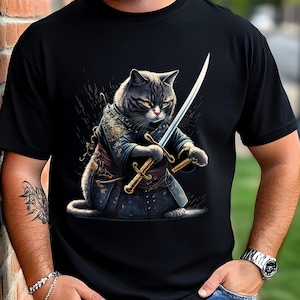 May include: A black t-shirt with a graphic of a cat holding two swords. The cat is wearing a dark blue and gold samurai-style outfit. The background is black with a subtle pattern of white lines.