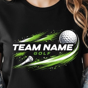Peut inclure: T-shirt noir avec un thème de golf. Le t-shirt présente le texte "TEAM NAME GOLF" en blanc et vert, ainsi qu'un graphisme de balle et de tee de golf. Le design comprend des accents de coups de pinceau verts.