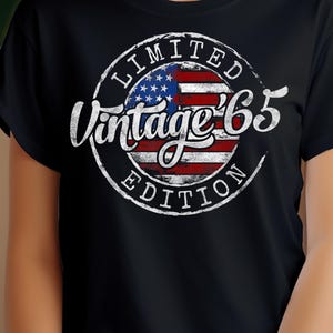 Peut inclure: T-shirt noir avec un graphique circulaire blanc vieilli représentant un drapeau américain et le texte "Limited Vintage '65 Edition".