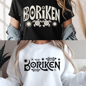 Peut inclure: T-shirt noir et sweat-shirt blanc, tous deux ornés du mot "BORIKEN" dans une police stylisée, accompagnés d'étoiles et de motifs de tortues. Vêtements décontractés pour un usage quotidien.