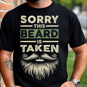 May include: A black t-shirt with the text "Sorry this beard is taken" in white and green lettering. A large cartoon beard is below the text.