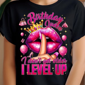 Peut inclure: T-shirt noir avec un motif de lèvres en paillettes roses et le texte "Birthday Queen I don't get older I LEVEL UP".