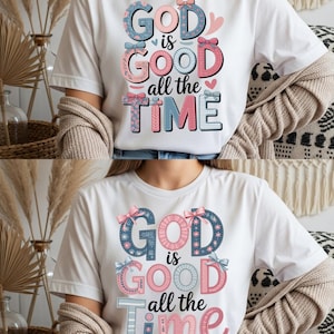 Peut inclure: T-shirt blanc avec l'inscription "GOD is GOOD all the TIME" dans un design floral coloré. Le texte utilise des couleurs bleu, rose et gris, avec des nœuds et des cœurs décoratifs. Un vêtement décontracté pour tous les jours.