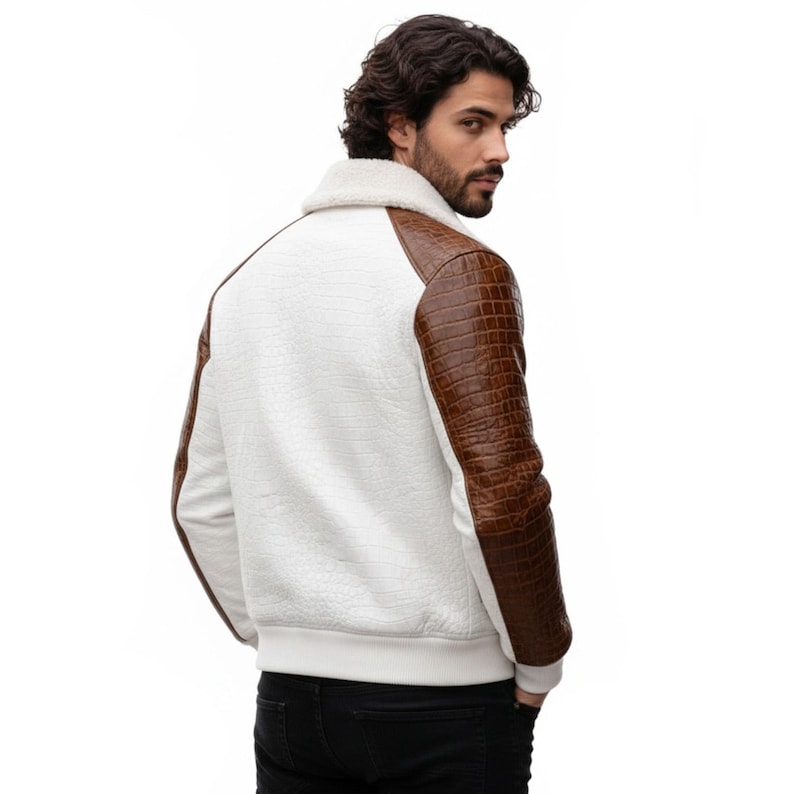 May include: White bomber jacket with brown faux-leather sleeves and a cream-colored shearling collar. The jacket has a textured pattern on the white fabric and a ribbed hem and cuffs. A stylish outerwear piece.