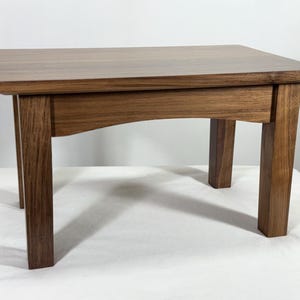 Peut inclure: Petite table rectangulaire en bois avec une finition marron foncé. La table a quatre pieds robustes et un design simple et élégant. La table mesure environ 61 cm de long, 46 cm de large et 41 cm de haut.