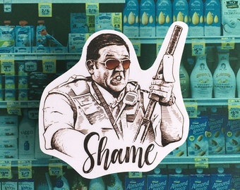 May include: A black and white illustration of a man holding a gun with the word "Shame" written in cursive below him. The illustration is on a white sticker with a grocery store aisle in the background.