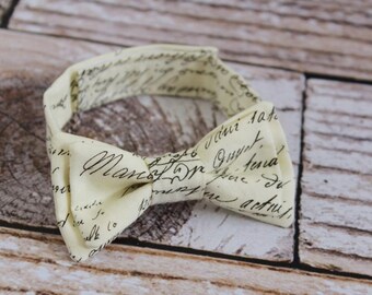 Handmade baby boys bookish bow tie in cream with black script and adjustable strap