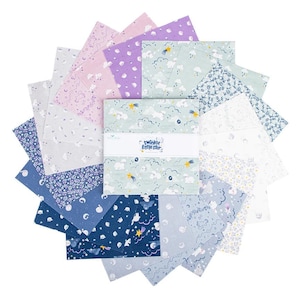 May include: A stack of square fabric swatches arranged in a circular fan pattern. The fabric features various patterns including clouds, stars, moons, and floral prints in shades of blue, purple, white, and mint. A white paper band reads Twinkle Little Star.