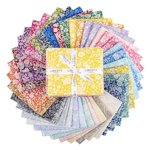 Pode incluir: Uma pilha de quadrados de tecido dispostos em um leque circular. Cada peça apresenta uma estampa floral distinta em várias cores, incluindo amarelo, azul, rosa, roxo, verde e laranja. Uma fita branca traz a inscrição LIBERTY FABRICS.