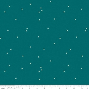 Pode incluir: Tecido azul-petróleo com um padrão salpicado de pequenos pontos verde claro. O tecido é marcado com medidas em polegadas ao longo da borda inferior. O texto "Riley Blake Designs" é visível.