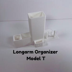 May include: A white Longarm Organizer Model T, a 3D-printed desk accessory. It features a tall, rectangular compartment, two small cubbies, and a small tray. The text "Longarm Organizer Model T" is visible.