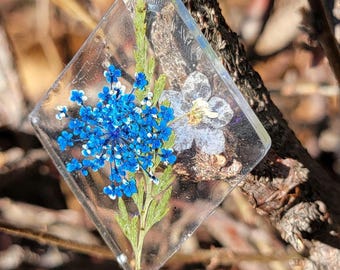 Stunning flower pendant cast in resin. Diamond shaped pendant with dark blue and light blue flowers cast in transparent resin.