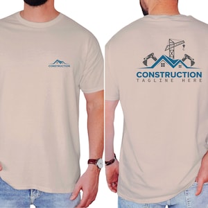 May include: Beige t-shirt with a blue construction logo on the front and back. The front logo features a house silhouette with the word "CONSTRUCTION" below. The back of the shirt displays a construction scene with the text "CONSTRUCTION TAGLINE HERE".