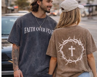 May include: Two people wearing matching t-shirts. One shirt is dark gray with "FAITH OVER FEAR" in white. The other is brown with a white crown of thorns and cross design. Both shirts are short-sleeved.