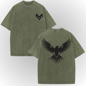 a green t-shirt with a graphic design on the back, featuring a stylized bird or eagle with outstretched wings.