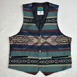 May include: A Southwestern-style vest with a geometric pattern in teal, navy, red, and tan. The vest has a V-neck, a black lining, and silver-tone buttons. The label reads "Pioneer Wear".