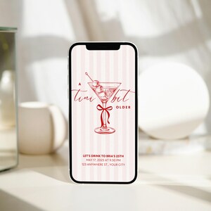 Martini-themed birthday invitation featuring a red martini glass with olives and a cute red bow, set against a pink striped background. Text reads 'A Tini Bit Older' with customizable details for a birthday party. Perfect for Dirty Thirty celebrations, coquette-themed events, and cocktail parties. Editable digital invitation template.