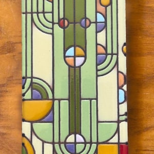 May include: A green, yellow, blue, and orange geometric tile with a repeating pattern of circles and lines.