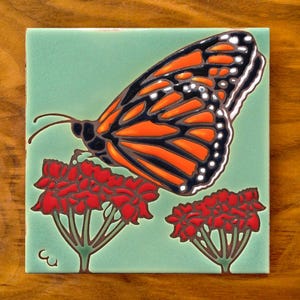 Hand glazed ceramic 6"x6" monarch butterfly with milkweed flowers | tile trivet on green