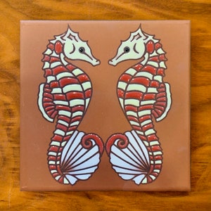 May include: Two white and red striped seahorses facing each other with their tails curled around a white seashell. The seahorses are on a brown background.