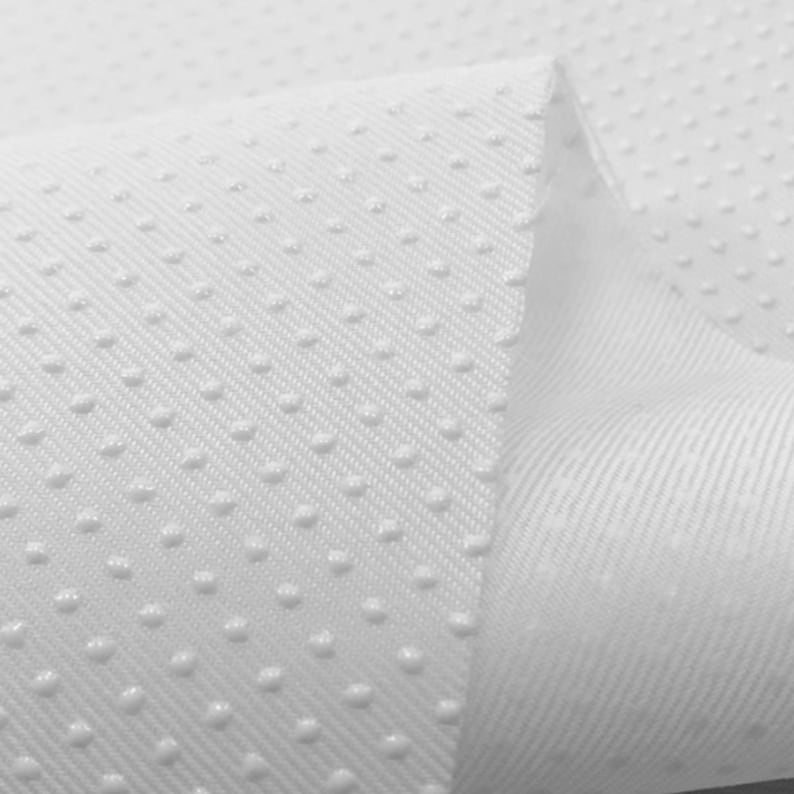 May include: White fabric with a textured, dotted pattern. The fabric has a subtle diagonal weave.