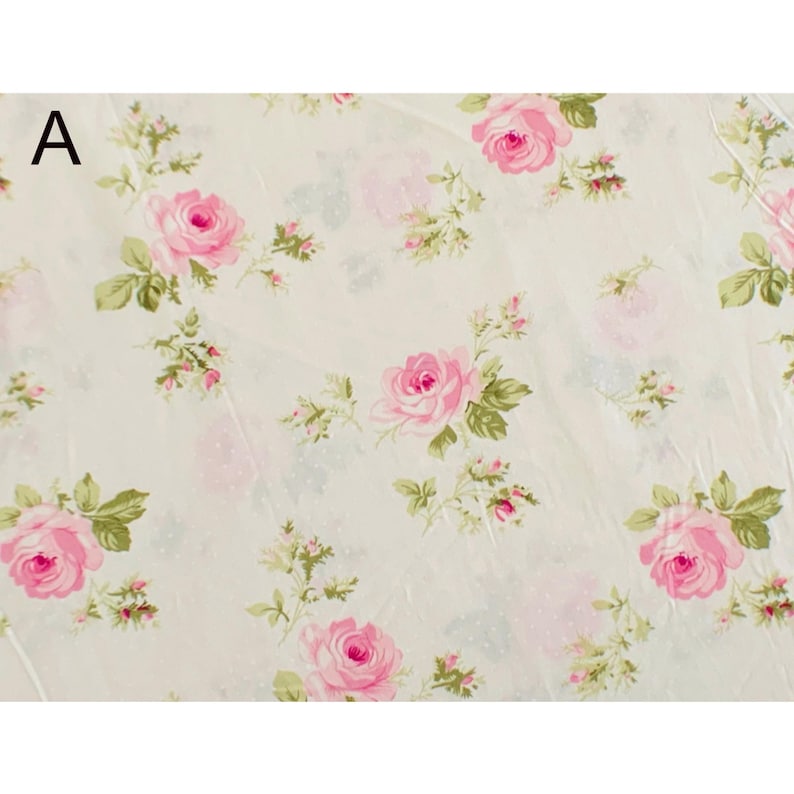May include: A floral pattern featuring pink roses and green leaves on a cream-colored background. The design includes smaller pink buds and green sprigs, creating a romantic and vintage aesthetic. The letter "A" is in the upper left corner.