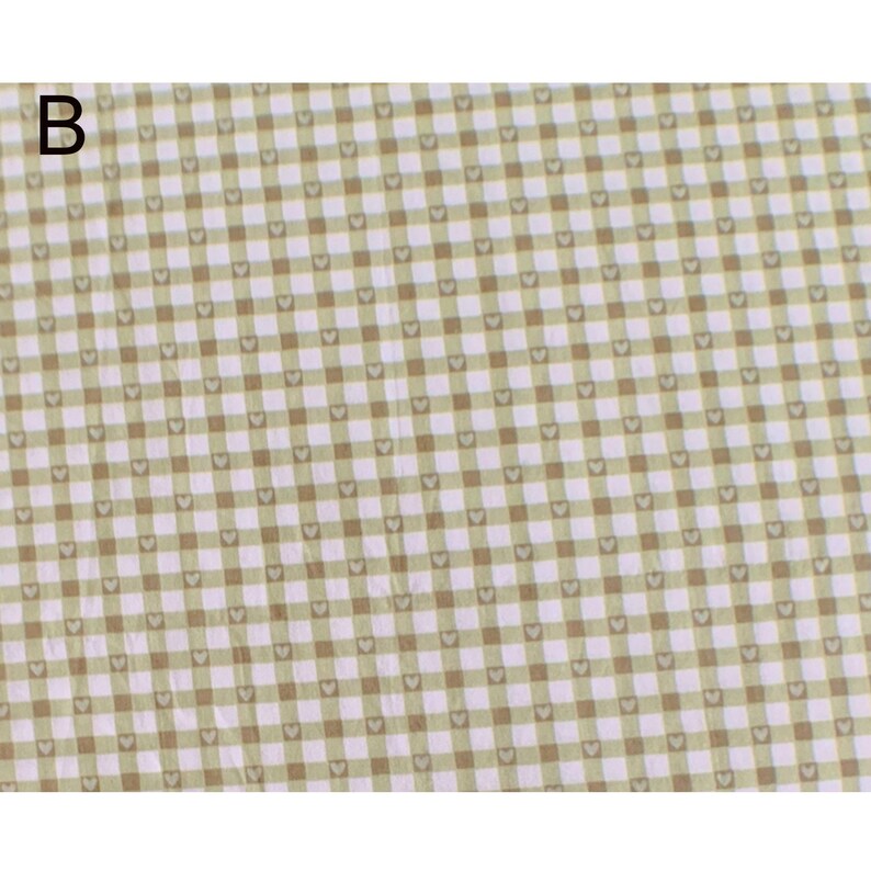 May include: A close-up of a fabric with a repeating pattern of small hearts within a grid of light green and brown squares. The letter "B" is in the upper left corner. The fabric has a soft, textured appearance.