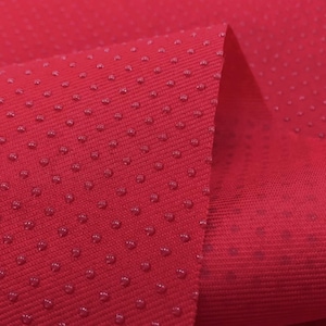 May include: Red fabric with a textured surface. The fabric has small, raised dots that create a subtle pattern.