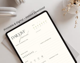 May include: A digital tablet displaying a "Daily IVF Journal" with prompts for tracking cycle, gratitude, water intake, mood, and appointments. The text "Printable & Digital - Instant Download" is visible. White headphones and a decorative plant are in the background.