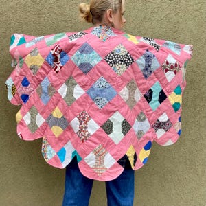 May include: A pink quilted jacket with a scalloped edge. The jacket is made of various fabric patches in a diamond pattern. The patches are in a variety of colors and patterns, including floral, polka dot, and geometric designs.