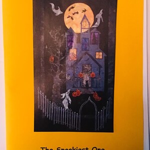 May include: A Halloween wall hanging featuring a spooky house with a full moon and bats. The house is blue and has orange pumpkins in front of it. The text on the image reads "The Spookiest One 18" x 31" Halloween Wall Hanging".
