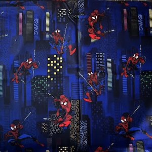 Peut inclure: Tissu bleu avec un motif répété d'un personnage Spiderman rouge et noir se balançant dans un paysage urbain. Le paysage urbain est composé de bâtiments hauts avec des fenêtres et des lumières.