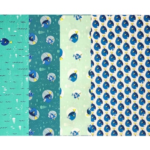 May include: A collection of patterned fabric swatches featuring aquatic themes. Designs include blue fish, jellyfish, and wavy lines in shades of teal, turquoise, and light green. The fabric is likely cotton or a similar material, suitable for quilting or crafting.