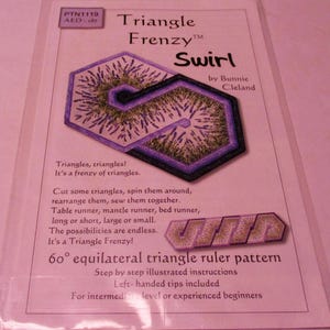 May include: A pink and white paper pattern for a quilting project called "Triangle Frenzy Swirl" by Bunnie Cleland. The pattern features a purple and green swirl design with lavender flowers. The pattern includes instructions for a 60 degree equilateral triangle ruler pattern. The text on the pattern says "Triangles, triangles! It's a frenzy of triangles. Cut some triangles, spin them around, rearrange them, sew them together. Table runner, mantle runner, bed runner, long or short, large or small. The possibilities are endless. It's a Triangle Frenzy! 60° equilateral triangle ruler pattern Step by step illustrated instructions Left-handed tips included For intermediate level or experienced beginners"