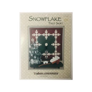 May include: A pattern for a snowflake tree skirt with a red, white, and green color scheme. The pattern is called "Snowflake Tree Skirt" and is by "Thimbleberries by Lynette Jensen".