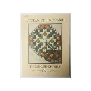 May include: A sewing pattern for a Christmas tree skirt called "Evergreen Tree Skirt" by Thimbleberries Classic Country. The pattern features a quilt design with a green, brown, red, and white color scheme.