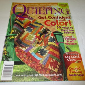 May include: The cover of "American Patchwork & Quilting" magazine displays a vibrant quilt over a green chair. Text includes "Get Confident with Color!" and "Stunning Log Cabin Quilts". The issue is from October 2009.