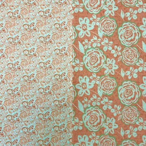 May include: Two fabric patterns side-by-side. The left side has a light blue background with a repeating pattern of copper-colored swirls and floral elements. The right side features a coral background with a floral design in light blue and green.