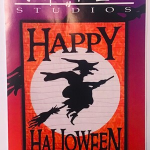 May include: A red and white applique banner pattern featuring a black silhouette of a witch flying on a broomstick in front of a full moon. The banner reads "Happy Halloween" and "Witch on the Wind 16 x 22" appliqué banner pattern".
