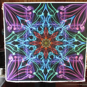 Peut inclure: Une tapisserie psychédélique avec un motif de mandala coloré et des motifs de fumée tourbillonnants dans des tons de violet, bleu, vert et rouge sur un fond noir.