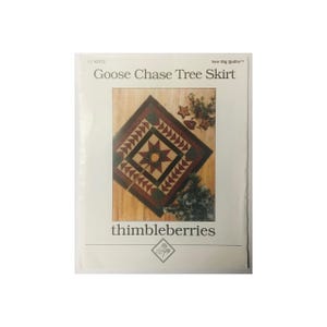 May include: A package for a Goose Chase Tree Skirt quilt pattern. The design features a central star motif surrounded by a diamond pattern in shades of red, green, and brown. The brand name "thimbleberries" is displayed.