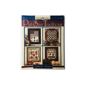 May include: A book titled "Pint-Size Traditions" by Lynette Jensen, featuring four quilt patterns with a patriotic, autumnal, and winter theme. The book cover is burgundy with a diamond pattern and features images of the quilt patterns.