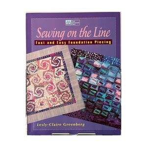 May include: A purple book titled "Sewing on the Line" with the subtitle "Fast and Easy Foundation Piecing." The cover displays quilt patterns and the author's name, Lesly-Claire Greenberg. The title is in white and red.