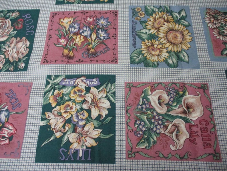 May include: A fabric panel with a patchwork design featuring various flowers and their names. The panel includes a rose, sunflower, crocus, iris, calla lily, and satin lily. Each flower is depicted in a square with a pink or blue background.