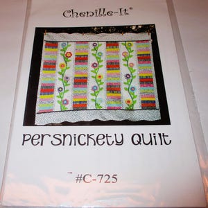 Peut inclure: Un paquet de patron de quilt avec un motif de quilt coloré. Le quilt présente des rangées verticales de rectangles de différentes couleurs, décorées de vignes florales. Le texte "persnickety quilt" est affiché sous l'image du quilt.