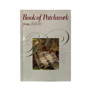 May include: A book titled "Book of Patchwork from Japan" with a cream-coloured cover. The cover features a photo of a patchwork quilt and decorative swirls. The book's title is in a serif font.