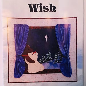 May include: A Christmas quilt pattern featuring a brown bear and a white polar bear looking out a window at a starry night sky with a single star shining brightly. The text "A Christmas Wish" is at the top of the pattern and the text "Sunset Silhouette Designs, Inc. By Carol Robinson P.O. Box 1605 Sumner, WA 98390" is at the bottom of the pattern.