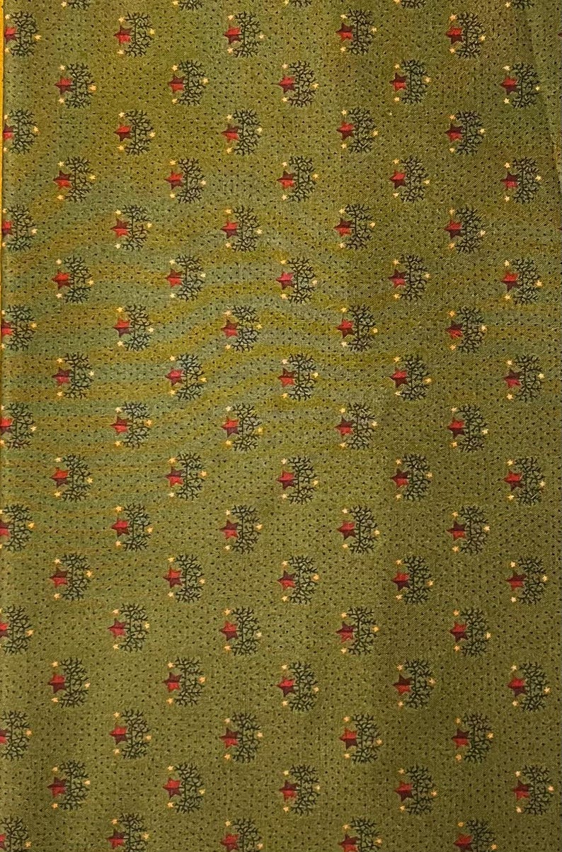 May include: Green fabric with a repeating pattern of stylized trees and red stars. The trees are dark green with small yellow dots, and the stars are a deep red. The background is a muted green.