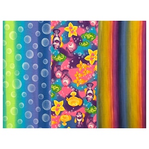 May include: A colourful fabric panel with three different patterns. One side has a green to blue gradient with white bubbles. The centre panel features cartoon fish and flowers on a pink background. The third panel has vertical stripes of yellow, orange, purple, and blue.